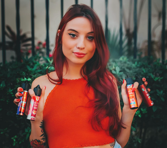 Woman holding multiple shortfill vape juice bottles outdoors.